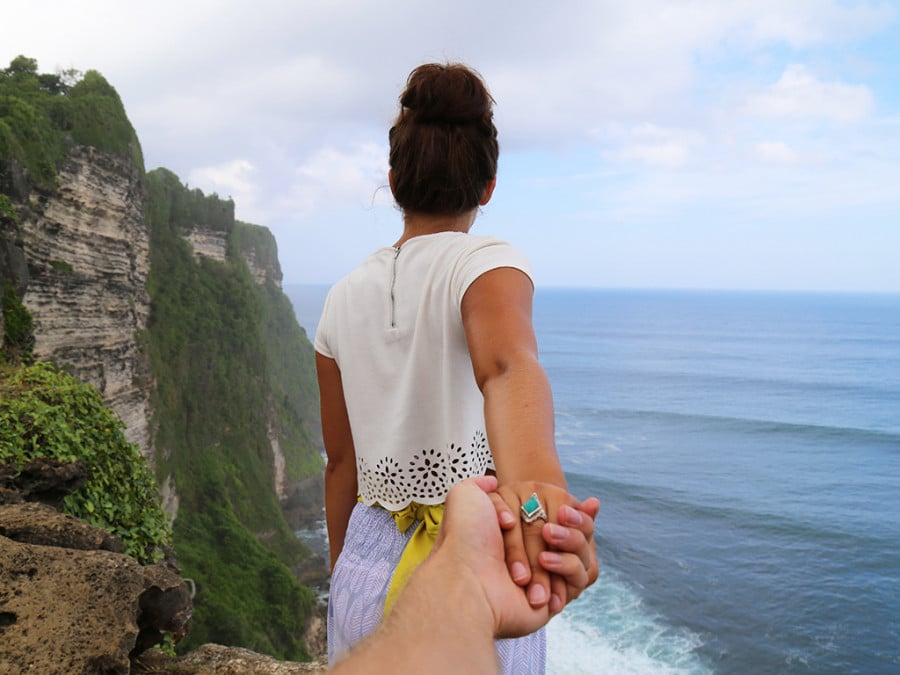 Lady holding someones hand on a cliff edge