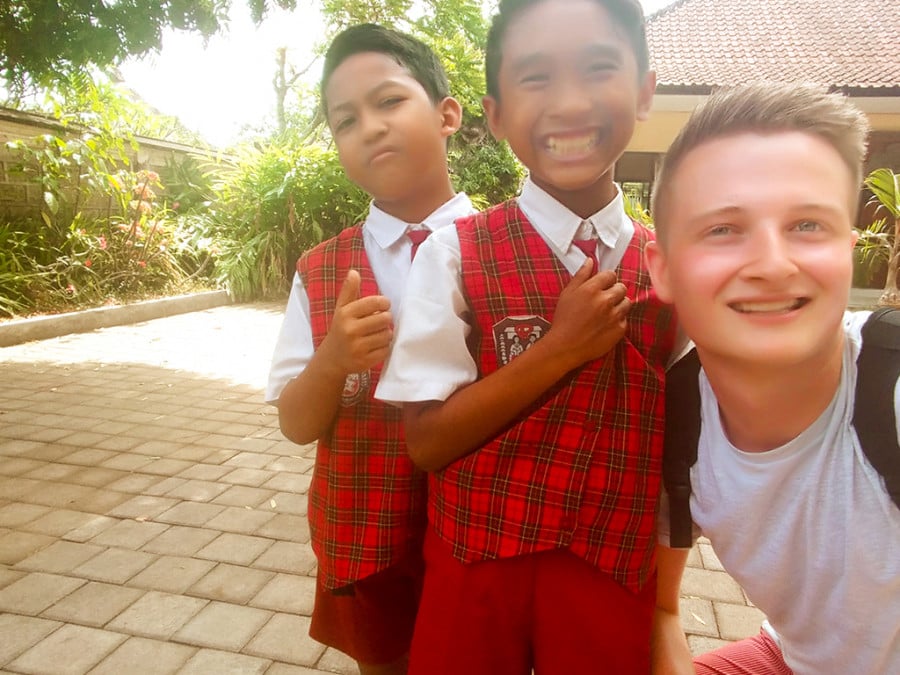 A man posing for a photo with two schoolkids