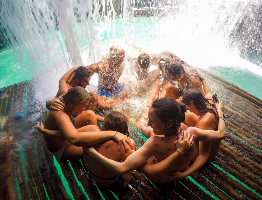 A group of travellers in a pool with water coming down from above