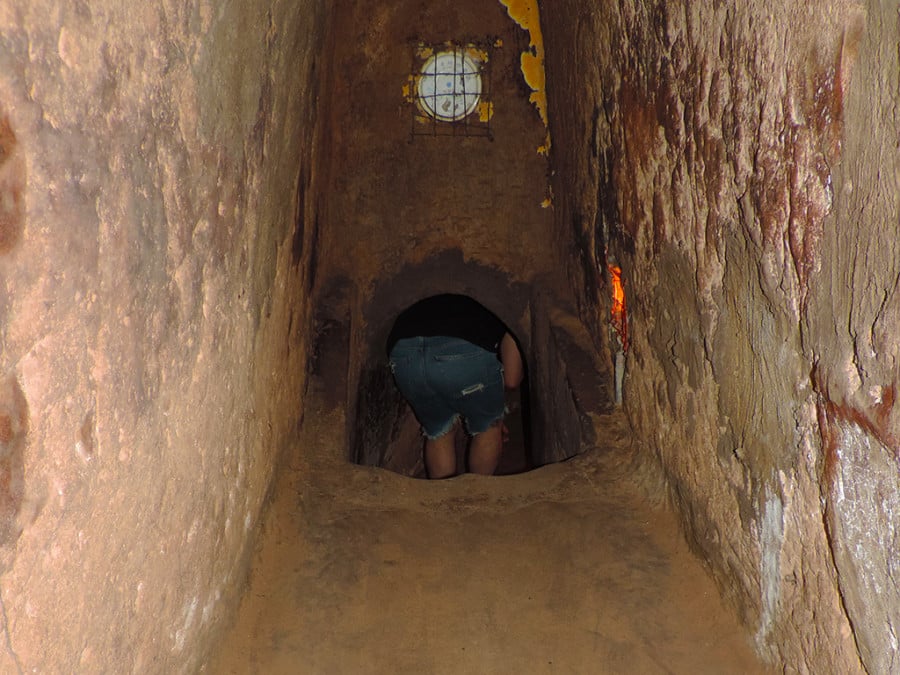 A person crouches through a small tunnel opening